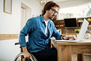 Young entrepreneur in wheelchair working on a computer at home.